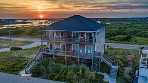A two-story house with a balcony, a staircase, and a view of the sunset. - Oceanview Island Retreat with views of The Atlantic and Waterway (North Topsail Beach)
