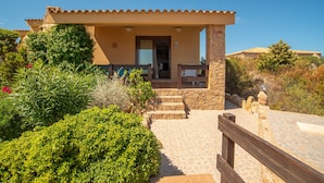 A villa with a stone exterior, a covered porch, and a stone staircase leading to the entrance.