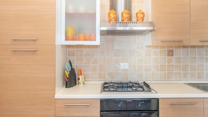 A kitchen with a gas stove, oven, and a cabinet with a window above it.