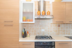 A kitchen with a gas stove, oven, and a cabinet with a window above it.