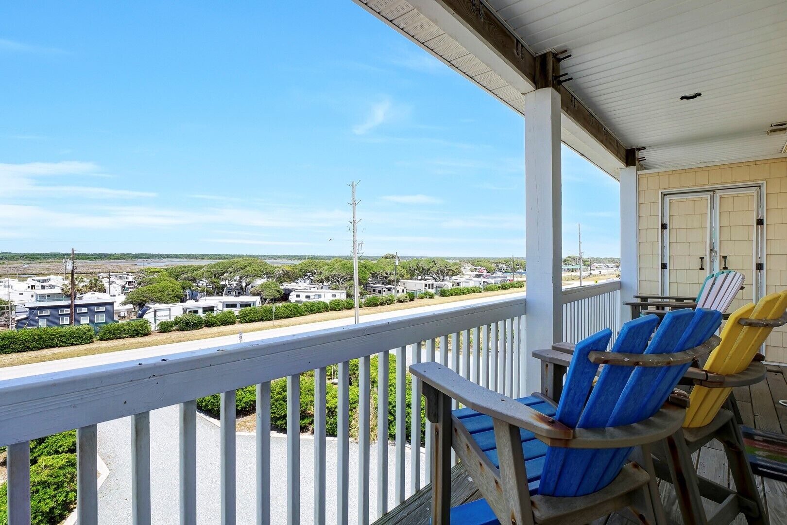 A covered porch with a view of a residential area and a road.