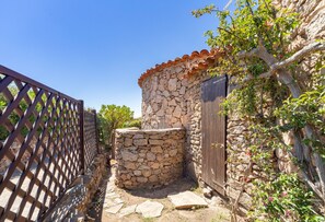 A stone building with a wooden door, a stone wall, and a wooden fence. - Cottage 'con terrazza e vista mare; parcheggio disponibile su strada' with Terrace, Sea View and On-Street Parking (Golfo Aranci)