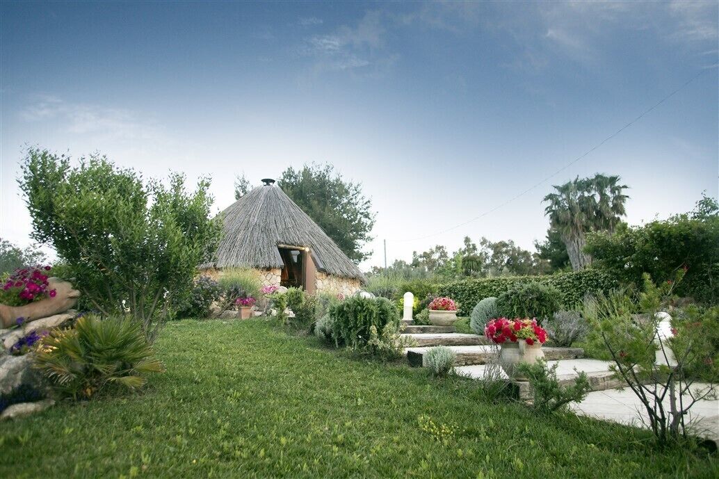 Une maison à toit de chaume avec un jardin devant.