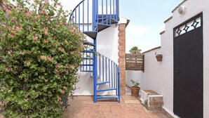 A spiral staircase with blue railings, a white wall, and a potted plant. - Enjoy Conil Near the Sea with Pool and Barbecue – Apartment A at Villa Mayo (Conil de la Frontera)
