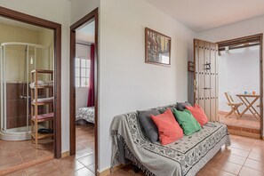 A room with a bed, a shower, a dining area, and a door leading to another room. - Enjoy Conil Near the Sea with Pool and Barbecue – Apartment A at Villa Mayo (Conil de la Frontera)