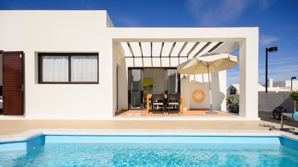 A modern house with a swimming pool, patio with outdoor furniture, and a covered seating area. - Villa Luna with Mountain View, Pool, Terrace and Wi-Fi (Playa Blanca)