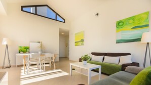 A modern living room with a sofa, a dining area with chairs, a white table, and a potted plant. - Villa Luna with Mountain View, Pool, Terrace and Wi-Fi (Playa Blanca)