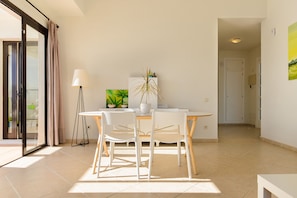 Een moderne eethoek met een tafel, stoelen, een lamp en een potplant.