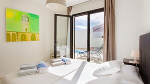 A hotel room with a bed, towels, a painting, and a view of the pool and sky. - Villa Luna with Mountain View, Pool, Terrace and Wi-Fi (Playa Blanca)