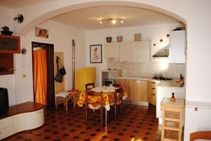 Uma cozinha compacta com área de refeições, uma mesa pequena com cadeiras e um balcão com pia.