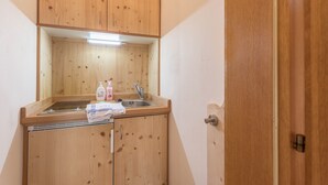 Eine kleine Küche mit Holzausstattung, einem Spülbecken und einer Arbeitsfläche.