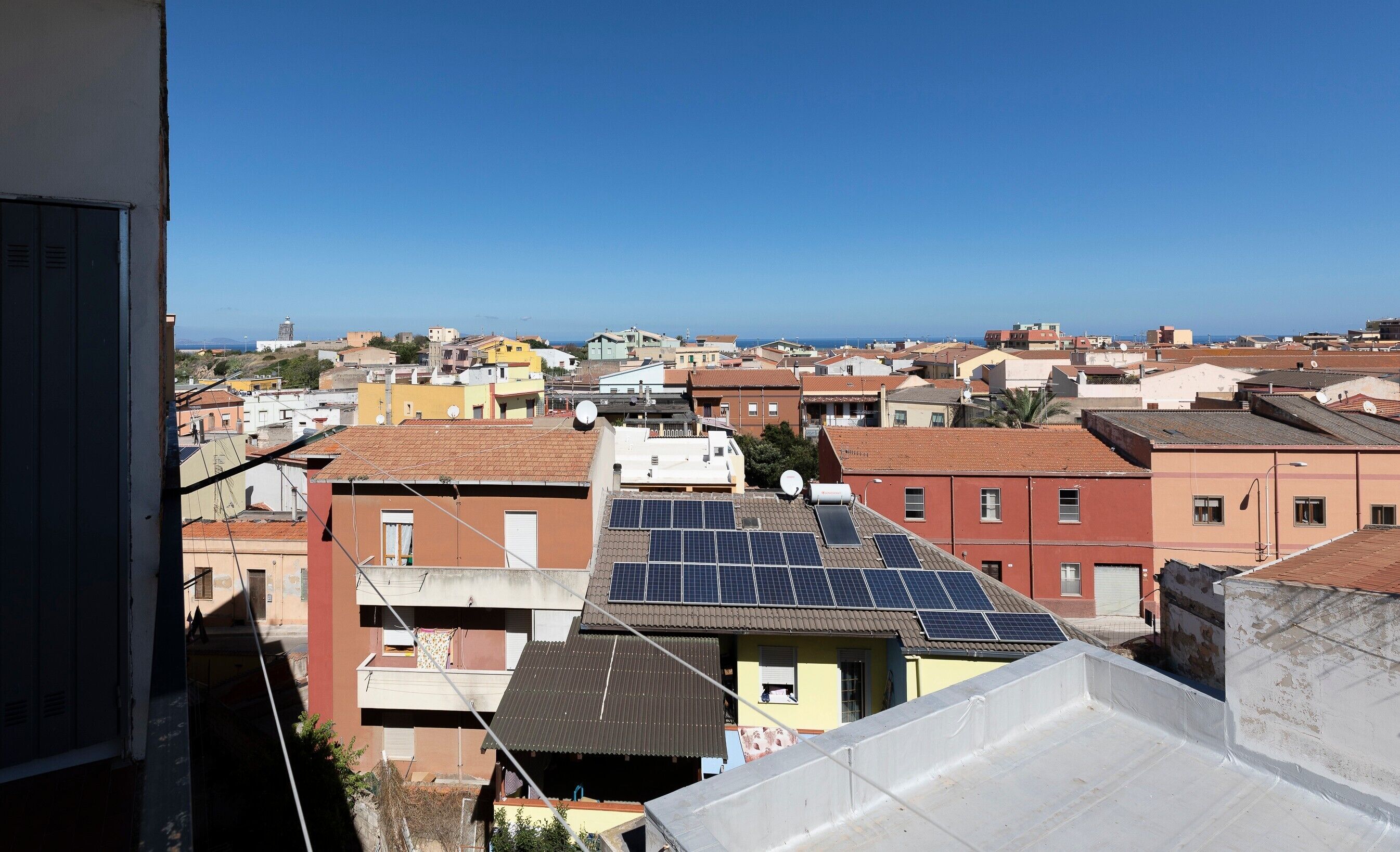 Zona residencial con edificios, algunos con paneles solares, y un cielo azul despejado.