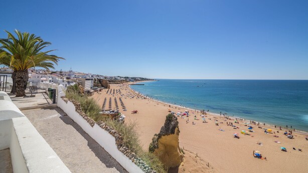 A coastal beach with a clear sky, a palm tree, and a rocky cliff. - Sunny Albufeira Beach Studio with Wi-Fi, Balcony, and Close to the Beach (Albufeira)