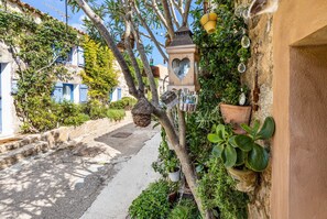A narrow street with buildings on either side, a hanging lantern, and potted plants.