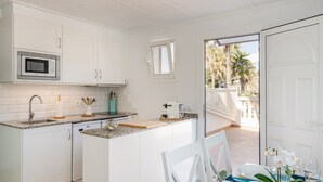 Una cocina con armarios blancos, un microondas y una zona de comedor con una mesa para dos.