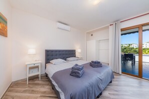 Un dormitorio con cama, mesitas de noche, una ventana con cortinas y vistas al exterior.