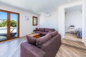 Ein modernes Wohnzimmer mit einer Eckcouch, einem Couchtisch aus Holz und Blick durch eine Glastür.