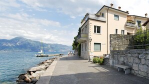 Un bâtiment situé sur la côte, doté d’une façade en pierre, d’une allée pavée et offrant une vue sur la mer.