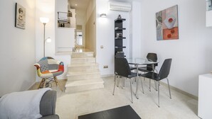 A modern living space with a staircase, a dining area with chairs, a colorful chair, a sofa, and a wall-mounted artwork. - Modern Apartment "Torre Close" to Beach in Historic Centre with Balcony and Air Conditioning (Cádiz)