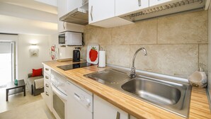 A modern kitchen with a built-in microwave, stainless steel sink, and wooden countertop. - Modern Apartment "Torre Close" to Beach in Historic Centre with Balcony and Air Conditioning (Cádiz)