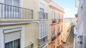 A narrow street with multi-story buildings, balconies, and a clear sky. - Modern Apartment "Torre Close" to Beach in Historic Centre with Balcony and Air Conditioning (Cádiz)