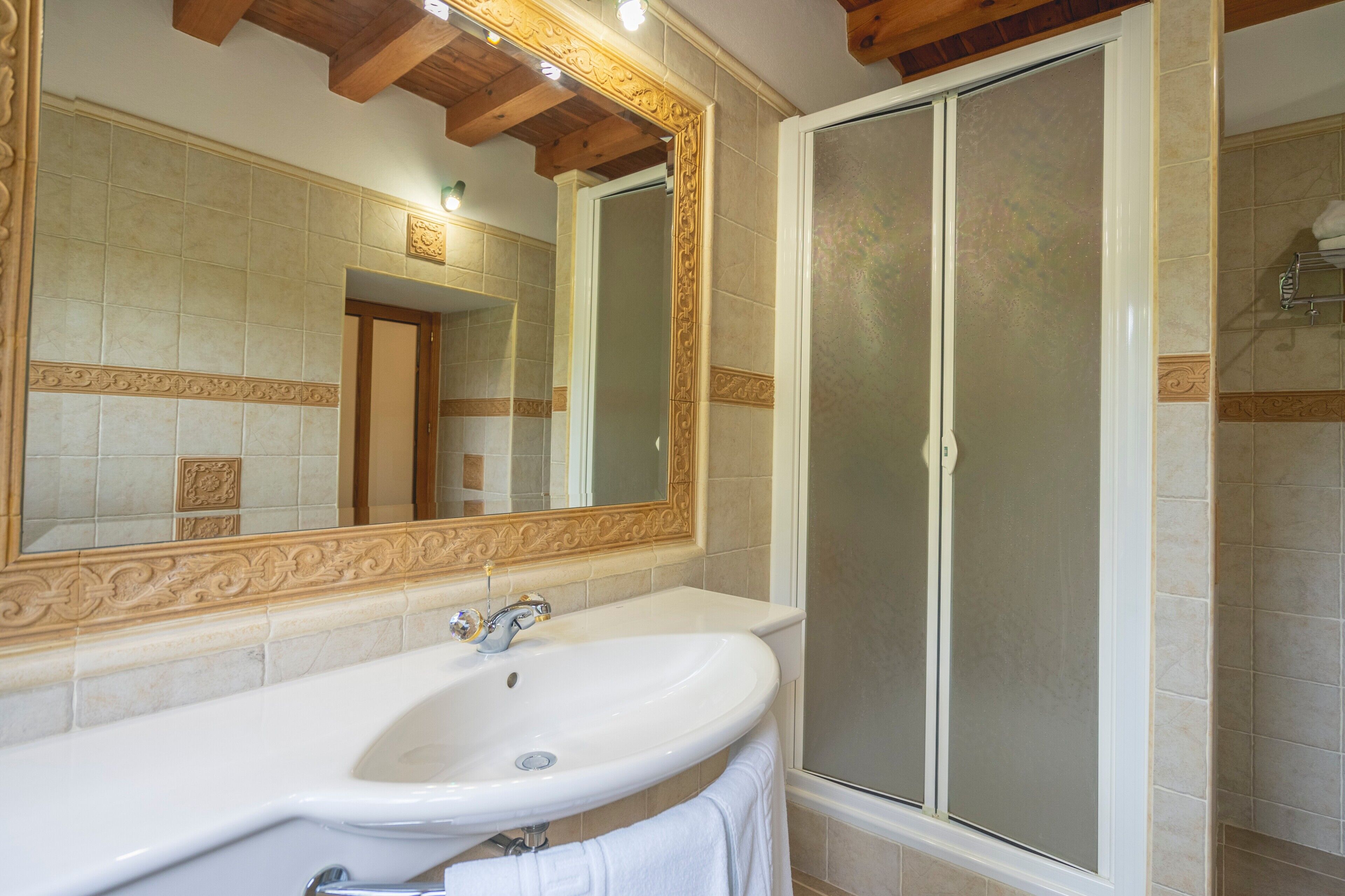 Une salle de bain avec un grand miroir, un lavabo et une douche.
