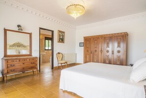 A bedroom with a large bed, wooden dresser, and a chandelier. - Beautiful Estate with Mountain View, Pool, Wi-Fi and Air Conditioning (Santa Eulalia del Río)