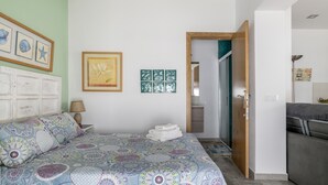 Une chambre à coucher comprenant un lit, une table de chevet, une lampe et une porte donnant sur une autre pièce.