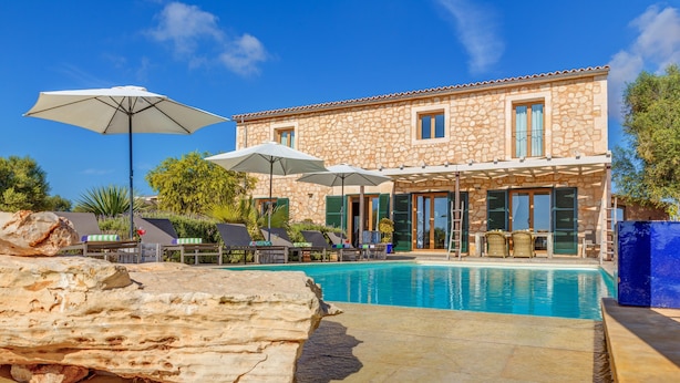 A stone building with a pool, outdoor umbrellas, and lounge chairs. - Stunning Villa Can Xesquet with Mountain View, Wi-Fi (ses salines)