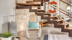 A modern living room with a staircase, a wicker chair, a round table, and a blue sofa. - Stunning Villa Can Xesquet with Mountain View, Wi-Fi (ses salines)