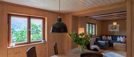 Ein Holzblock-Interieur mit Esstisch, Stühlen, einer Couch und einer Hängelampe.