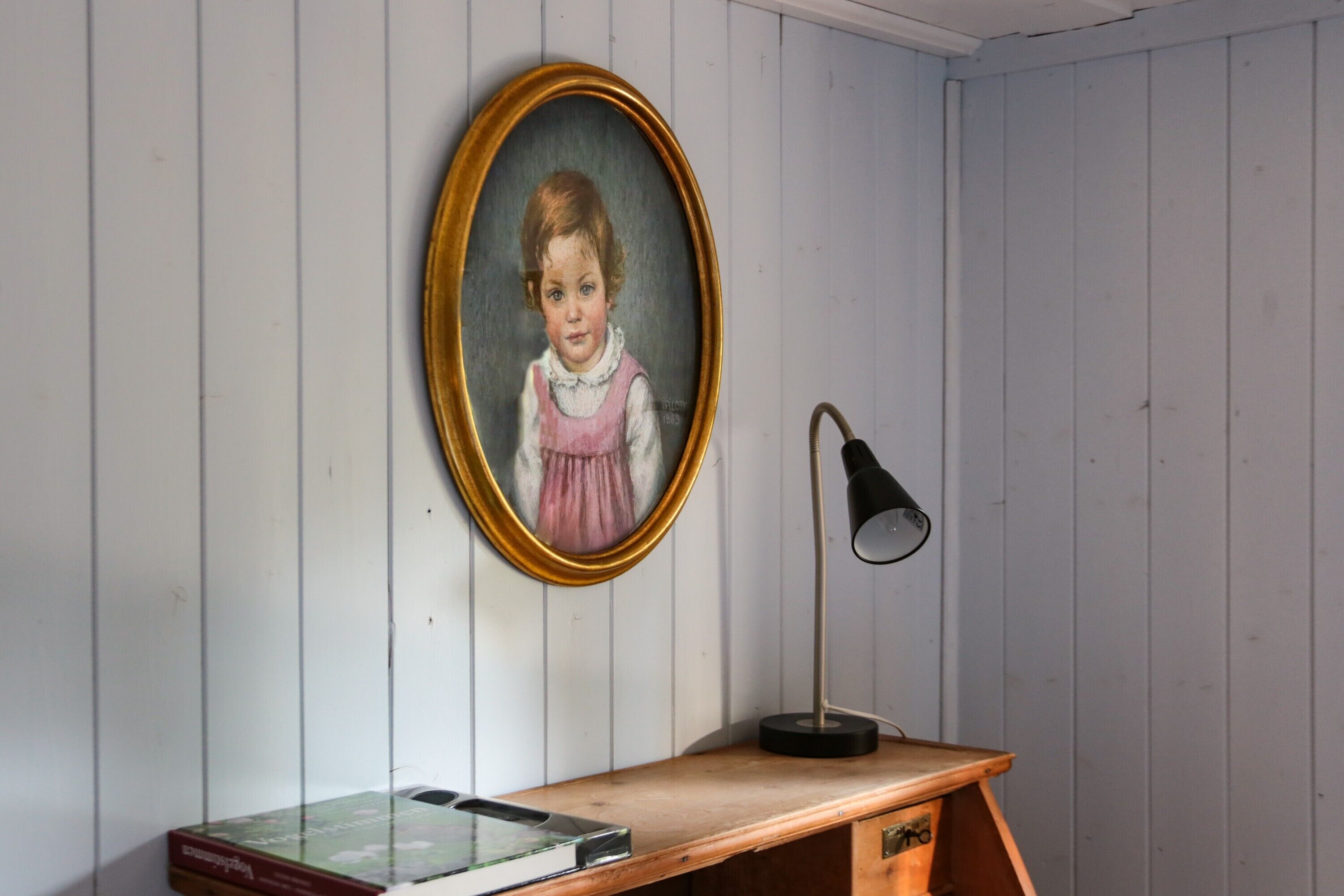 Ein Zimmer mit einem Holztisch, einem gerahmten Porträt und einer Lampe.