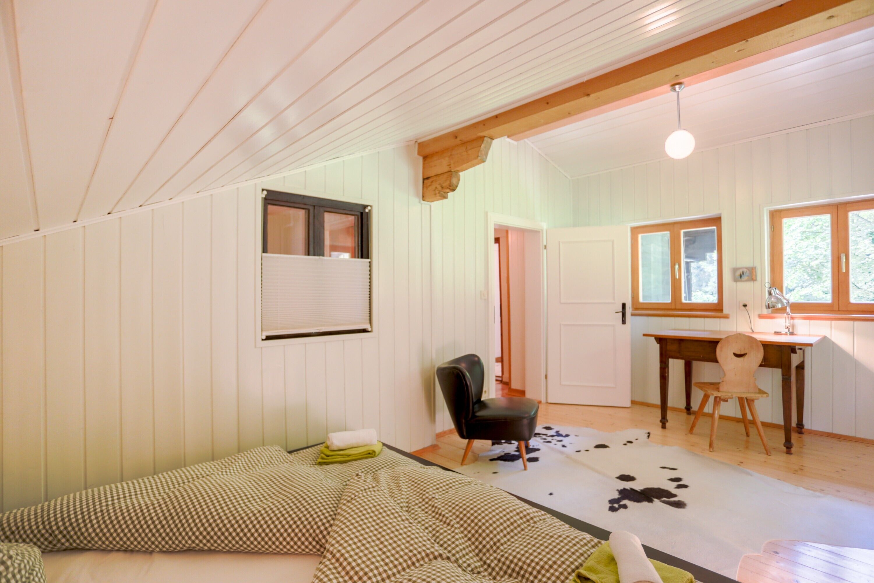 Une pièce comprenant un lit, une chaise, un bureau et un tapis en peau de vache.