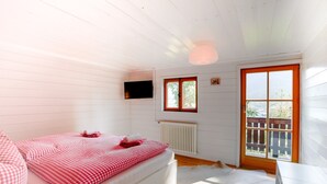 Een kamer met een bed, een televisie, een raam en een deur.