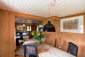 Un interior de madera con una mesa de comedor, sillas, un jarrón con girasoles y un mapa en la pared.