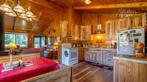 Una cocina acogedora de estilo cabaña, con armarios de madera, una estufa y un refrigerador.