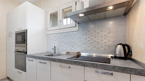 A modern kitchen with white cabinets, a built-in oven, a microwave, a stainless steel sink, and a kettle. - The Magnolia Three-Room Apartment: Charm on Three Levels in Lonato del Garda’s Courtyard (Lonato del Garda)