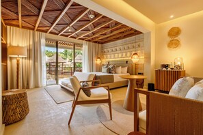 A modern hotel room with a wooden ceiling, a sofa, a chair, a small table, and a bed with a headboard. - Grand Sunset Princess - All Inclusive (Playa del Carmen)
