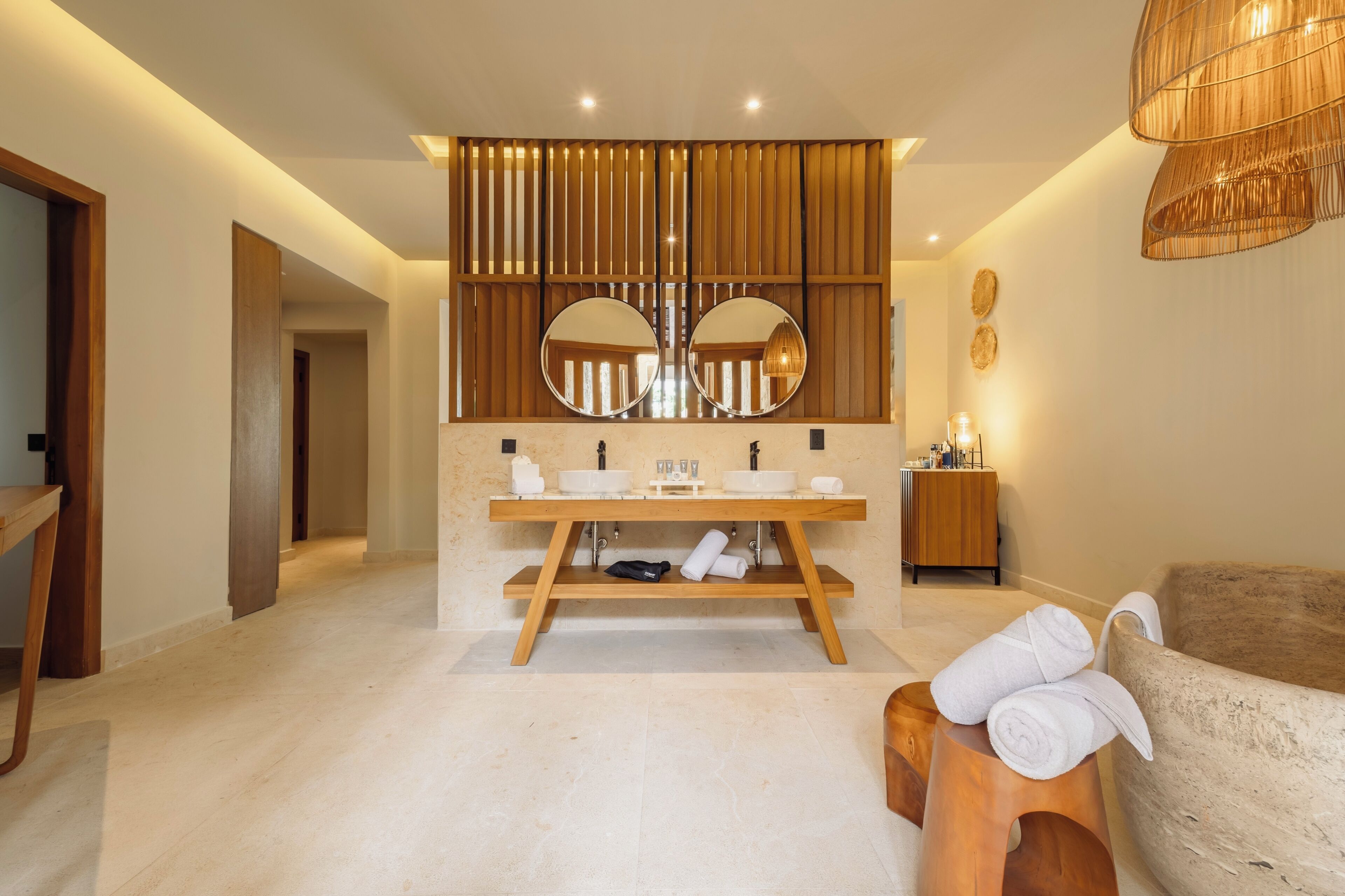 Un baño moderno con tocador de madera, dos espejos, un lavamanos y un perchero para toallas.