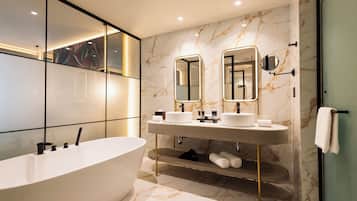 A modern bathroom with a freestanding bathtub, dual sinks, and a large mirror.
