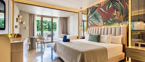 Habitación de hotel con una cama grande, un escritorio, una silla, un balcón con vistas y un mural temático tropical.