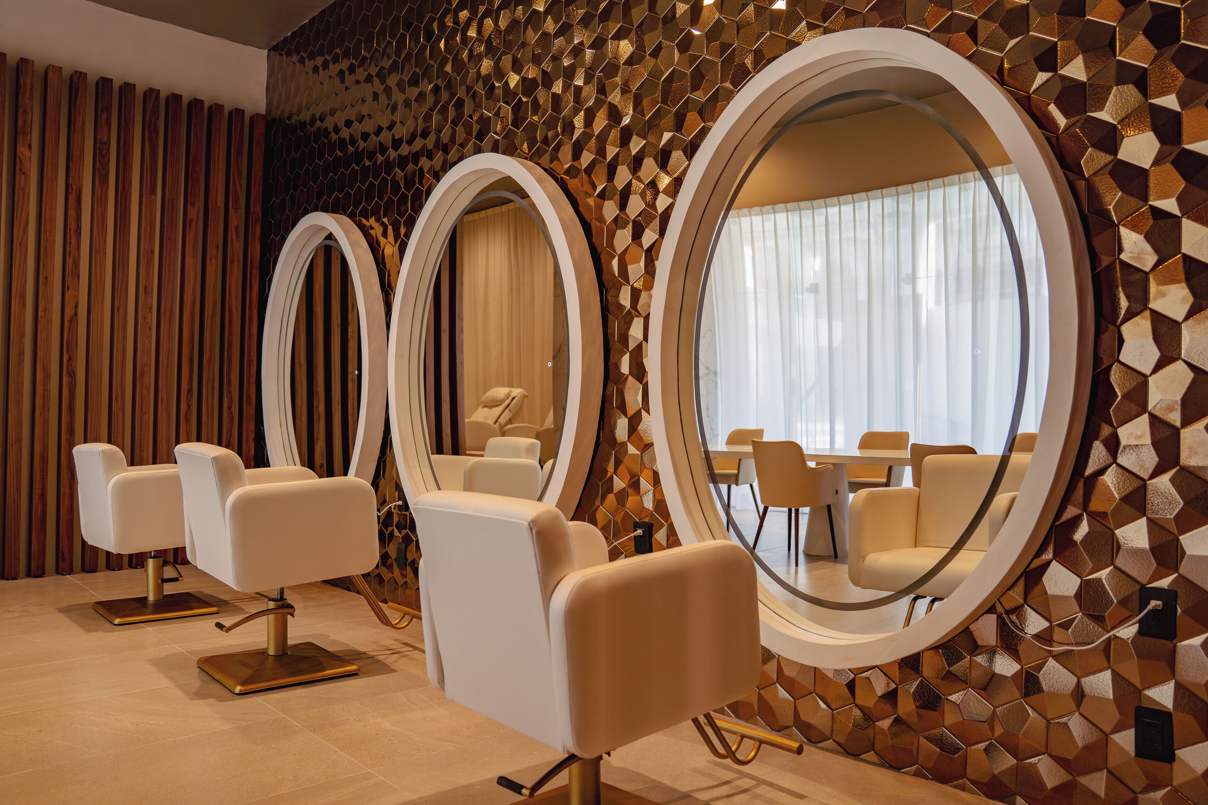 A modern salon with three white chairs, large mirrors, and a geometric patterned wall.