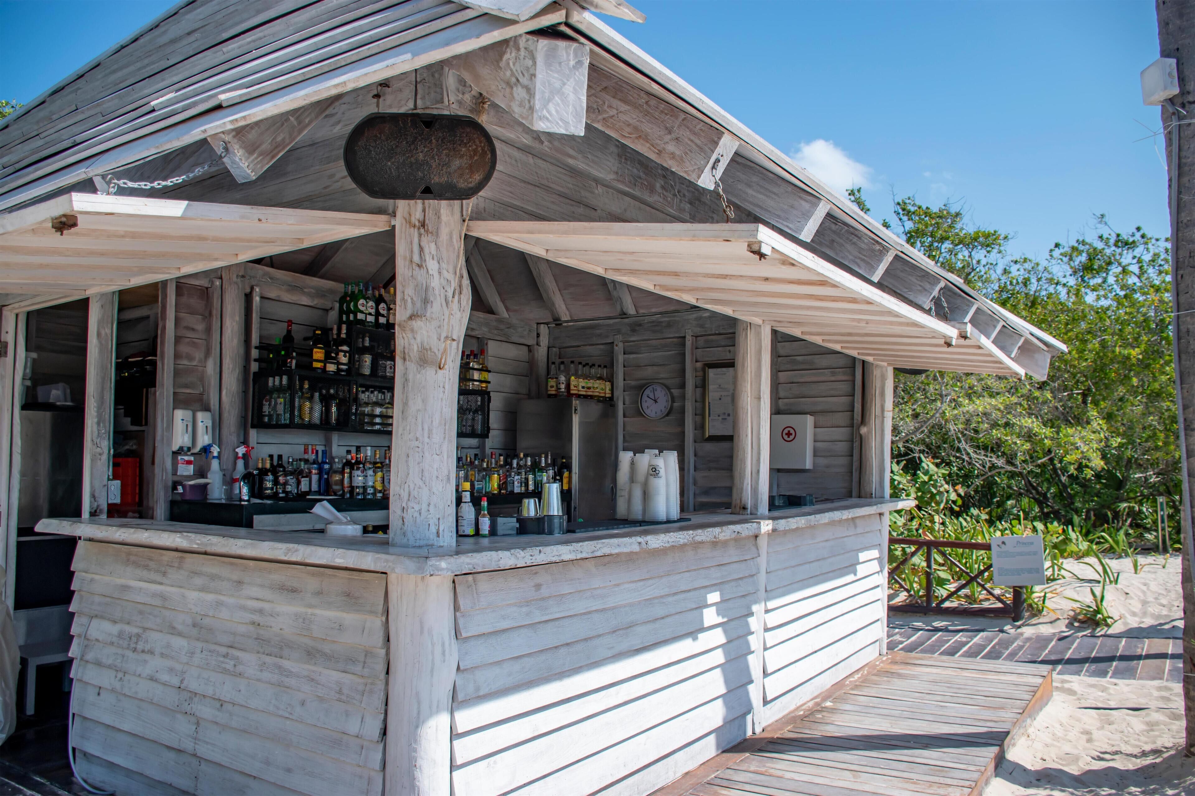 A wooden bar with a wooden counter and shelves of bottles.