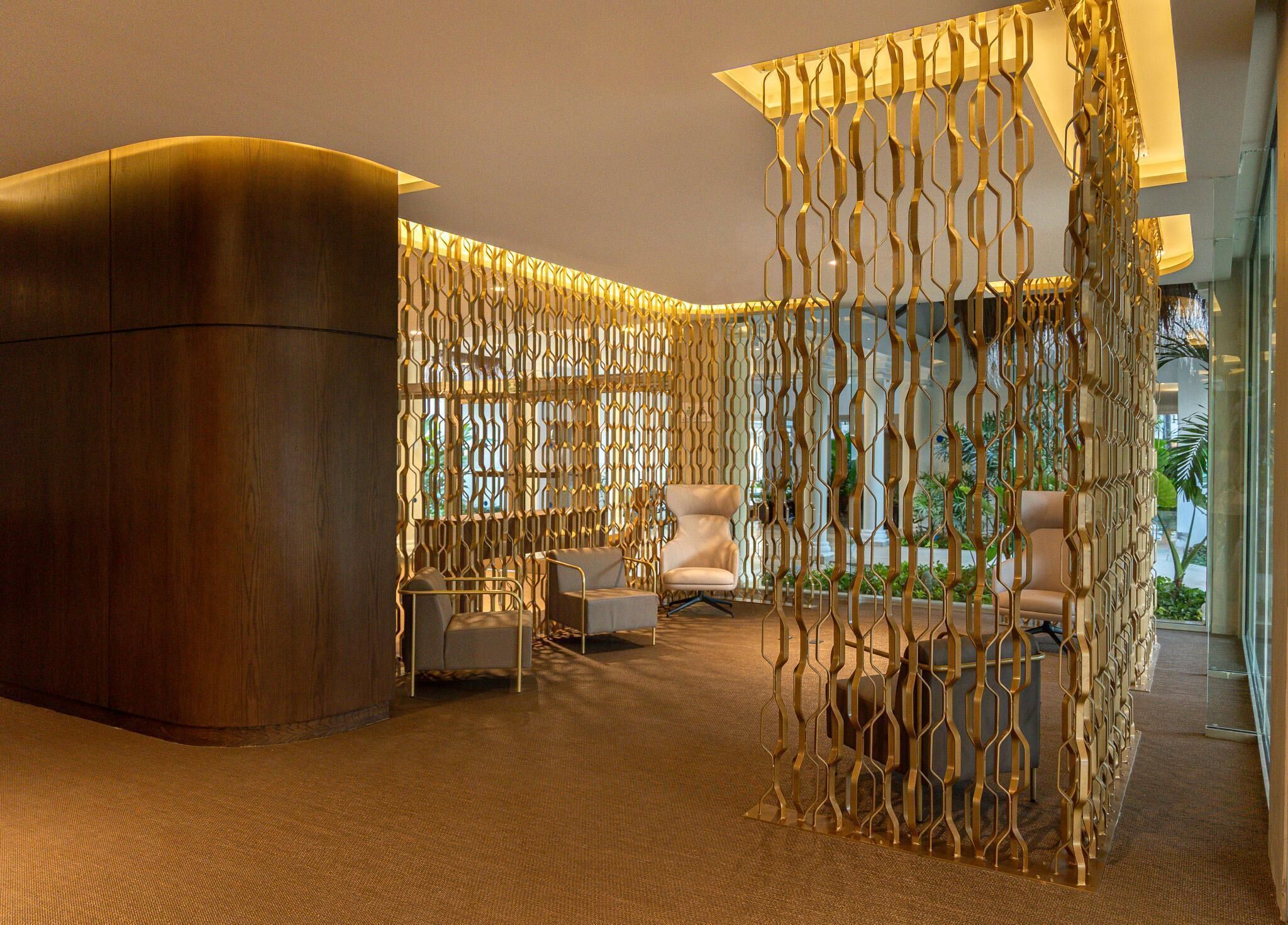 A modern lobby with a curved reception desk, seating area, and decorative metal partitions.