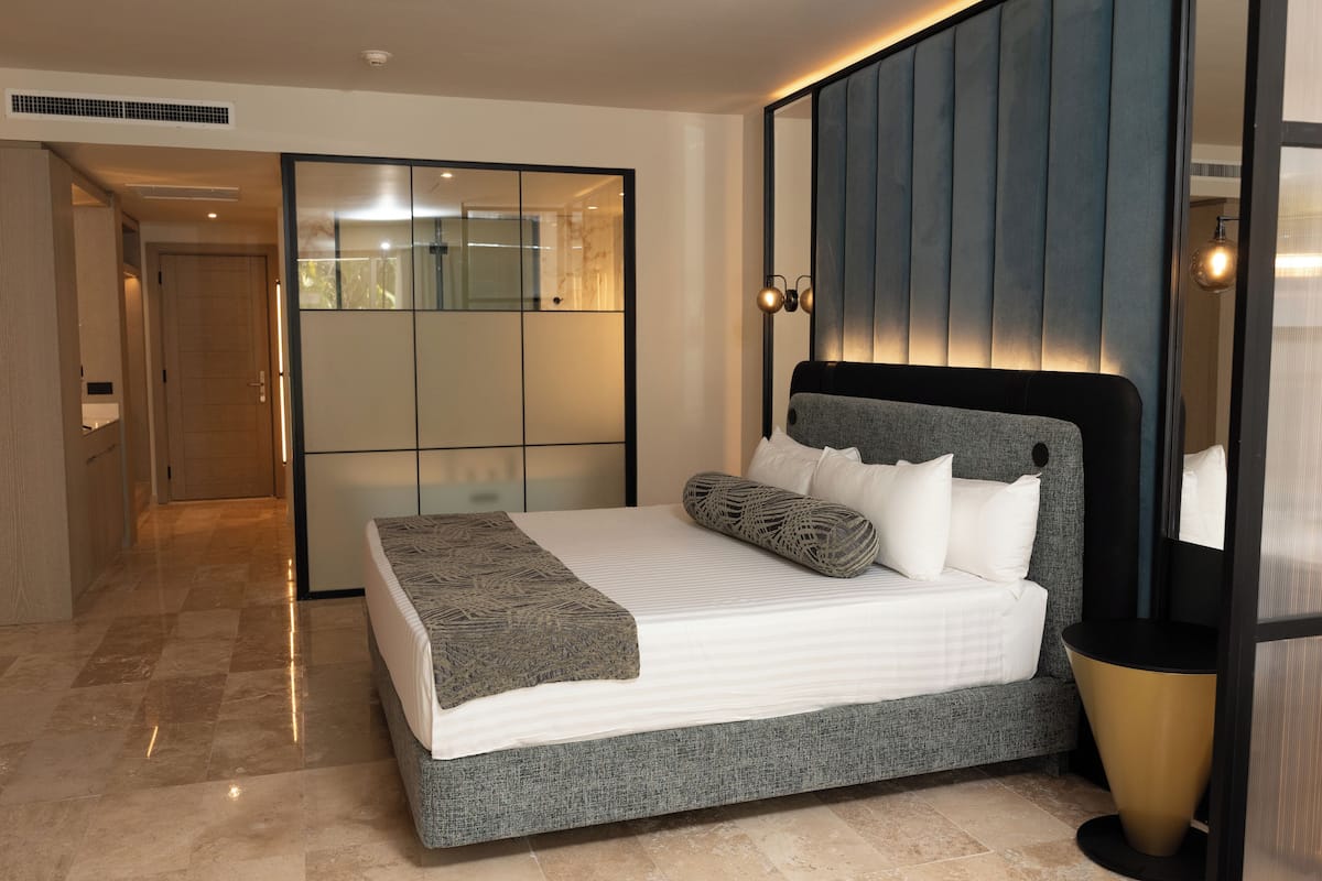Een moderne slaapkamer met een groot bed, een inloopkast met schuifdeuren en een spiegel.