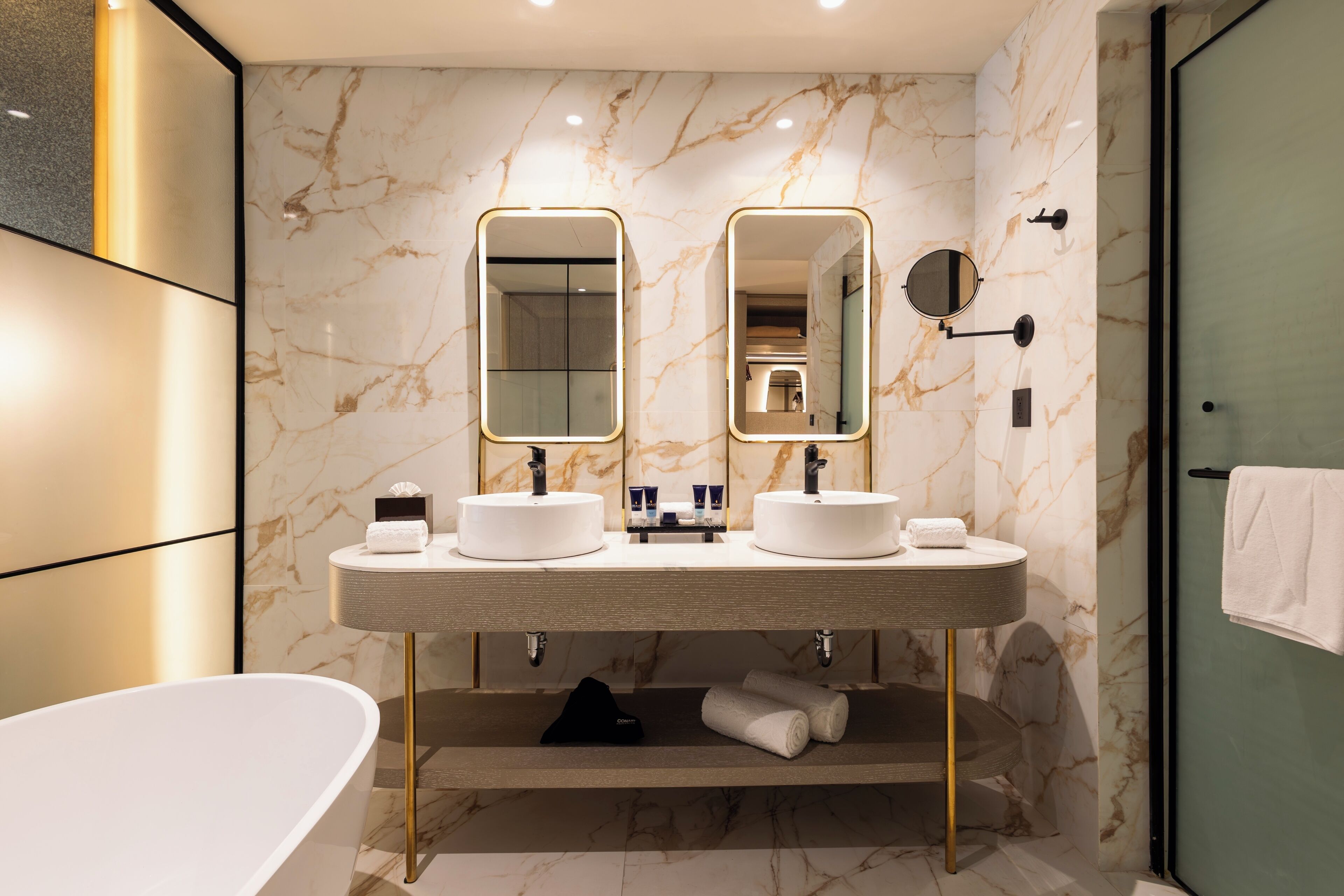 Un baño moderno con dos lavamanos, un espejo grande y una bañera.
