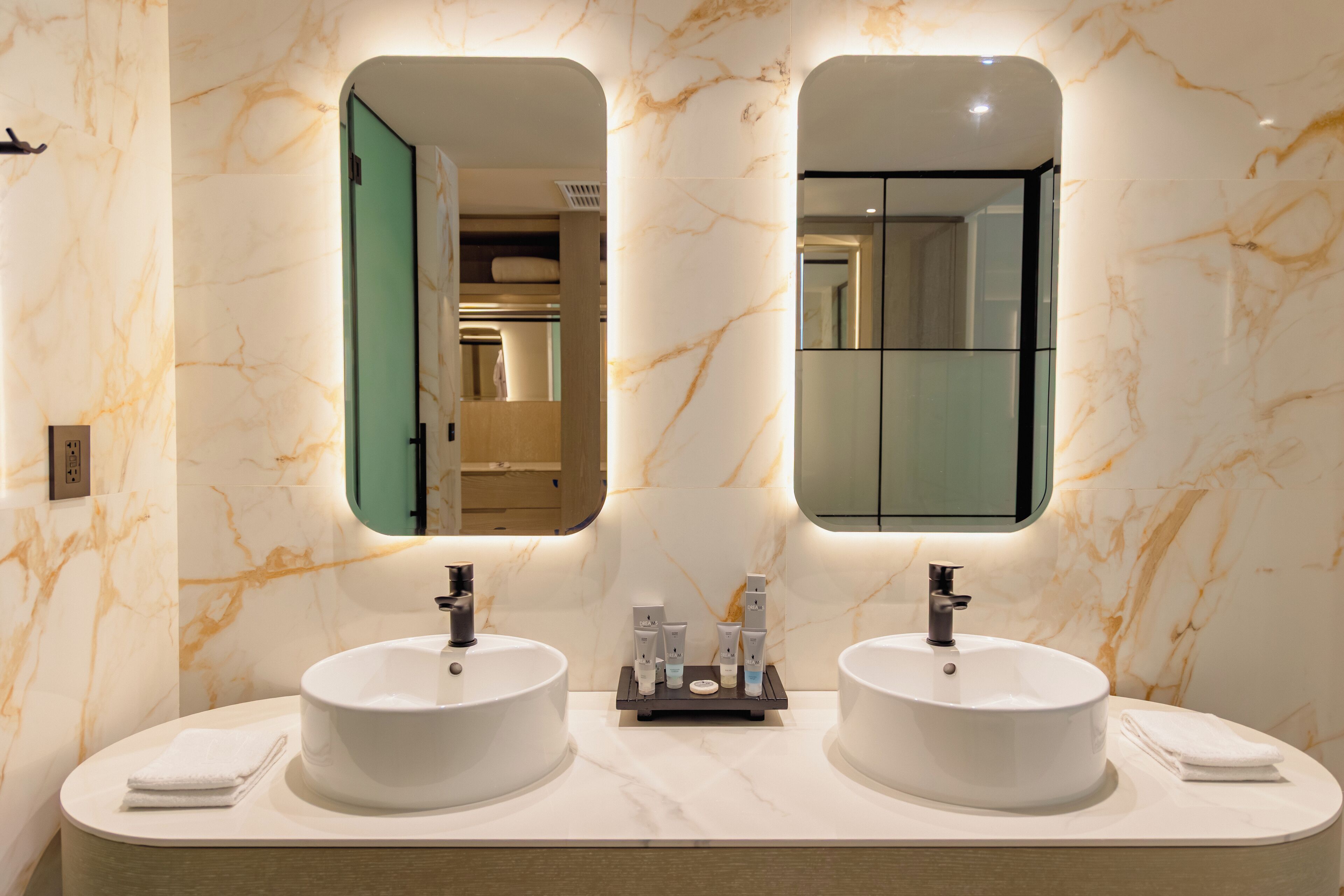 A bathroom with two sinks, marble walls, and mirrors.
