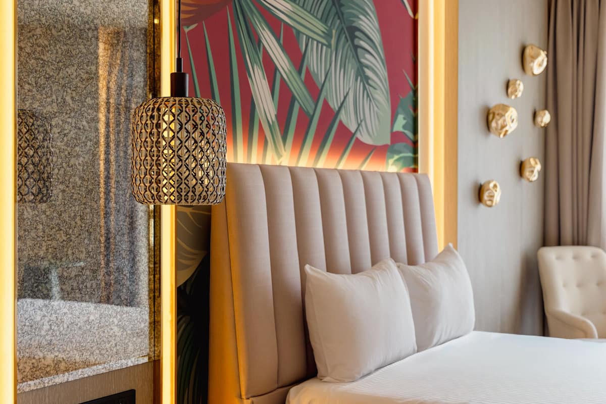 Een hotelkamer met een bed, een decoratieve wand met een bladmotief, een gestructureerde wand en een stoel.