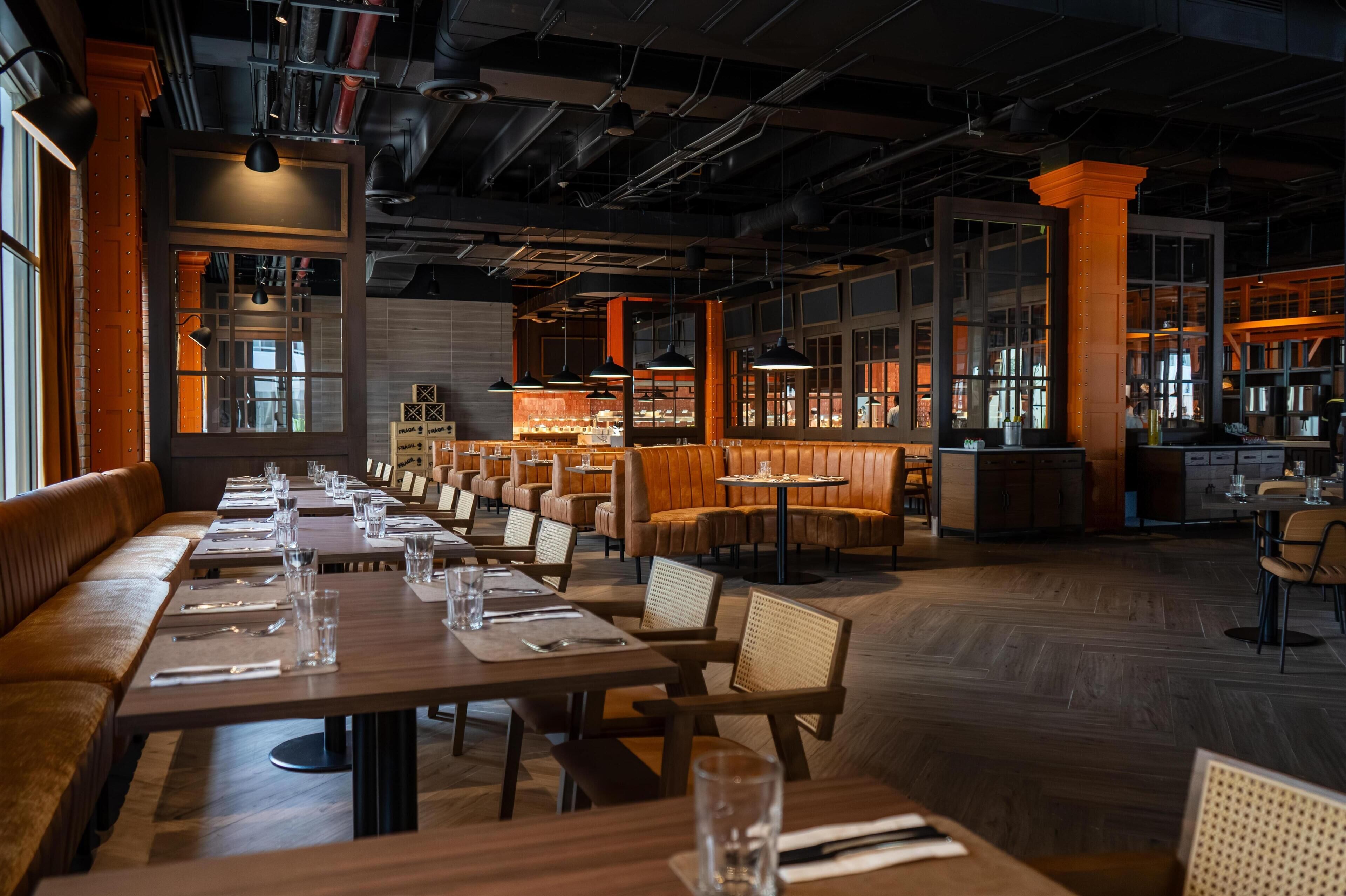 A restaurant with long communal tables, booths, and a bar area.