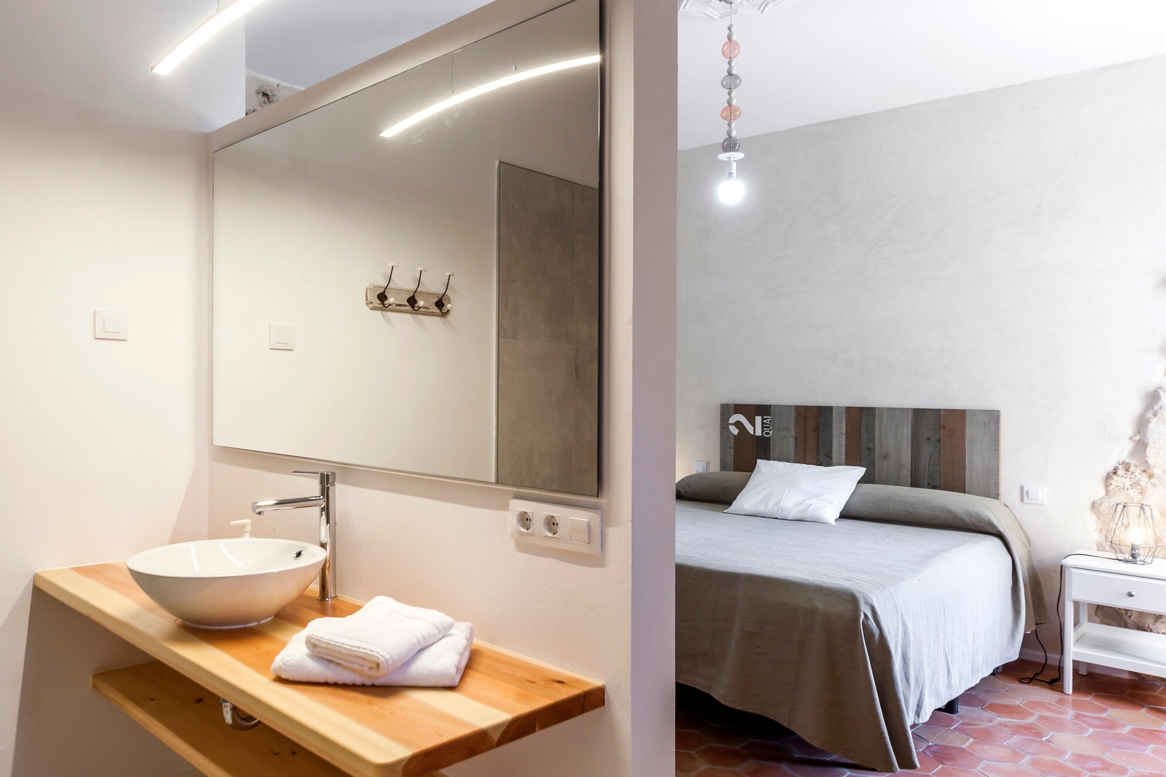 A bathroom with a large mirror, a white sink, and a wooden vanity.